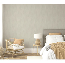 Chambre avec lit, table d'appoint, lampe et fauteuil en rotin