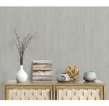 Scène décorative avec vase, branches, image et objets décoratifs sur une commode en bois devant un mur gris