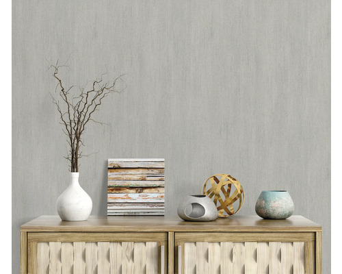 Scène décorative avec vase, branches, image et objets décoratifs sur une commode en bois devant un mur gris