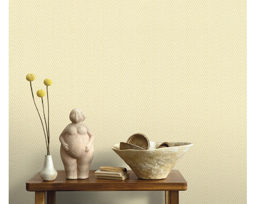 Arrangement décoratif sur une table en bois devant un papier peint à motif textile.