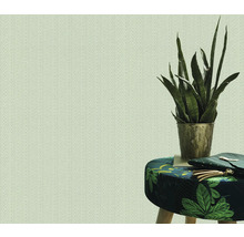 Papier peint clair à chevrons à côté d'un tabouret à motifs de feuilles et d'une plante d'intérieur