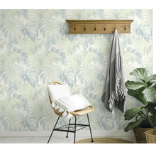 Pièce décorative avec papier peint à motif de feuilles, porte-manteau et chaise en rotin