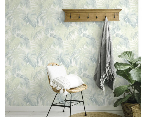 Pièce décorative avec papier peint à motif de feuilles, porte-manteau et chaise en rotin