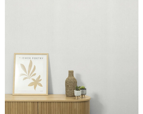 Scène décorative avec une commode, une image encadrée, une bouteille et des plantes en pot.