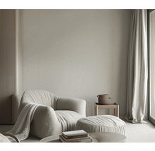 Salon avec fauteuil, tabouret, table d'appoint, rideau et décoration pour une ambiance lumineuse et conviviale.