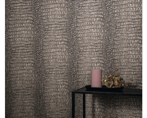 Gros plan d'un mur avec du papier peint imitation cuir de reptile, un plateau à bougies avec une bougie et une décoration florale