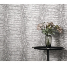 Gros plan d'un mur avec du papier peint en cuir de crocodile, une table et un vase de fleurs