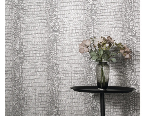 Gros plan d'un mur avec du papier peint en cuir de crocodile, une table et un vase de fleurs