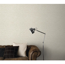 Salon avec papier peint clair aspect maçonnerie, canapé marron et lampadaire