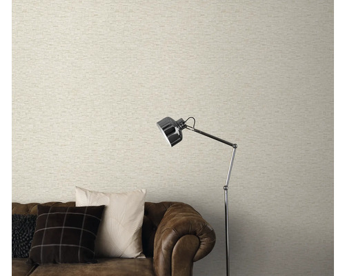 Salon avec papier peint clair aspect maçonnerie, canapé marron et lampadaire