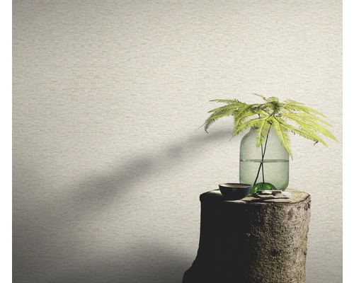 Gros plan d'un mur avec un papier peint aspect pierre, un vase avec une plante est posé sur une souche d'arbre.