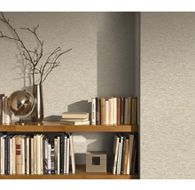 Étagère avec livres et objets de décoration devant un papier peint à motifs