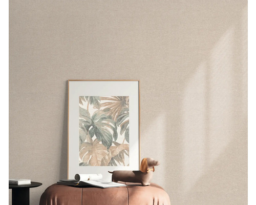 Scène avec une photo encadrée avec des motifs de plantes sur un tabouret devant un papier peint textile.
