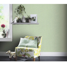 Chambre décorative avec papier peint intissé vert, fauteuil à motif végétal et fenêtre avec décoration