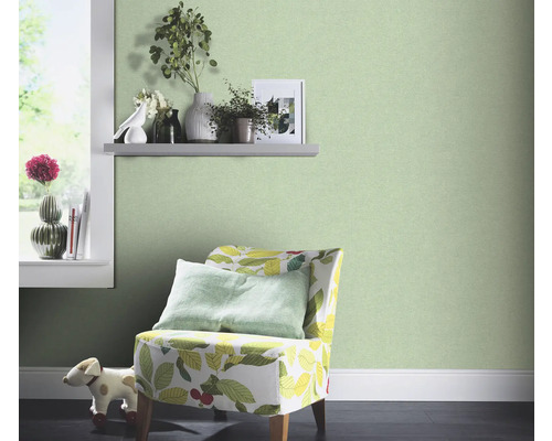 Chambre décorative avec papier peint intissé vert, fauteuil à motif végétal et fenêtre avec décoration