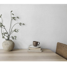 Nature morte décorative avec vase, branches, tasse et livres sur une table en bois.