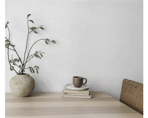 Nature morte décorative avec vase, branches, tasse et livres sur une table en bois.