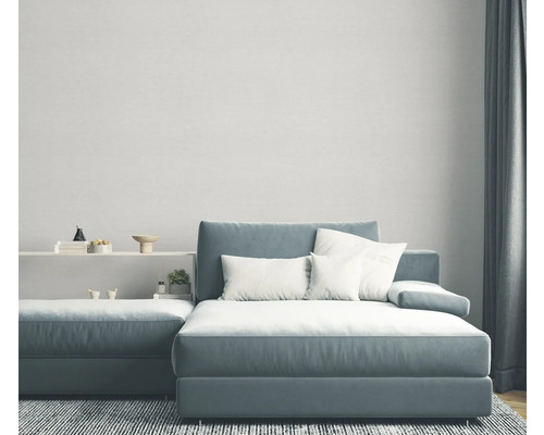 Salon avec canapé d'angle bleu-gris, coussins blancs et tapis gris