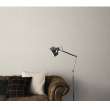 Salon avec canapé en cuir marron, coussins, lampadaire et papier peint beige