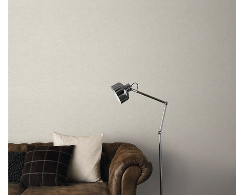 Salon avec canapé en cuir marron, coussins, lampadaire et papier peint beige