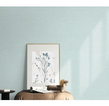 Gros plan d'un mur avec un papier peint clair, une image encadrée avec un motif floral et une figurine décorative