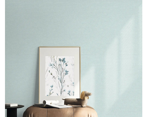 Gros plan d'un mur avec un papier peint clair, une image encadrée avec un motif floral et une figurine décorative