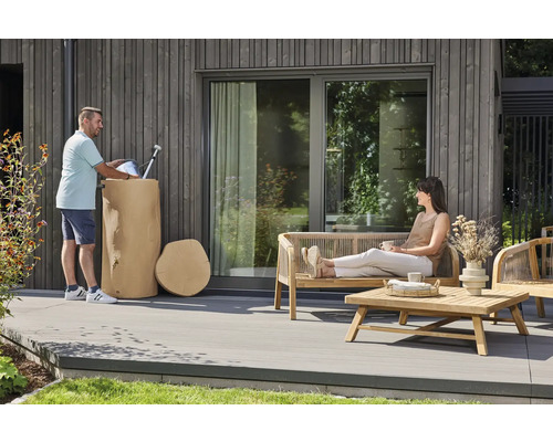 Espace extérieur moderne avec une terrasse en bois, des meubles de jardin en bois et un récupérateur d'eau de pluie décoratif en aspect tronc d'arbre.