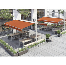 Terrasse avec stores, tables, chaises et plantations devant un bâtiment