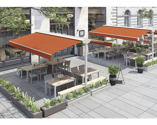 Terrasse avec stores, tables, chaises et plantations devant un bâtiment