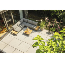 Salon de jardin d'angle moderne en bois et métal avec coussins gris sur une terrasse carrelée claire dans un jardin.