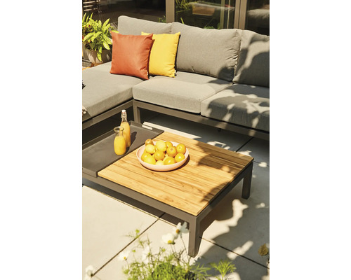 Salon de jardin d'angle moderne en métal avec coussins gris et table basse en bois sur une terrasse ensoleillée.