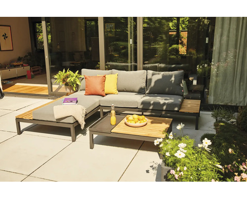 Salon de jardin moderne sur une terrasse avec canapé d angle gris, éléments en bois et table basse assortie devant une baie vitrée.