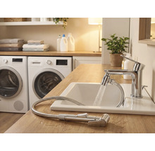 Salle de bain lumineuse avec lavabo, robinet avec flexible de douche et machines à laver