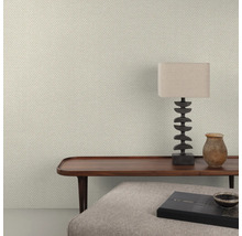 Nahaufnahme einer Wand mit Fischgrätmuster-Tapete, einem Holztisch, einer Lampe und dekorativen Gegenständen.