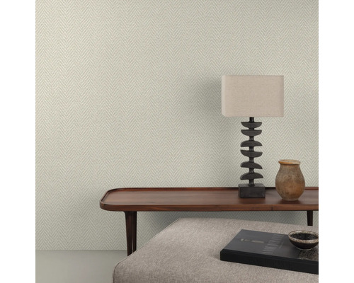 Nahaufnahme einer Wand mit Fischgrätmuster-Tapete, einem Holztisch, einer Lampe und dekorativen Gegenständen.