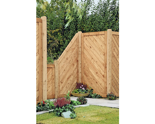 Clôture en bois avec planches diagonales et jardinières plantées dans le jardin