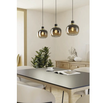 Trois suspensions avec abat-jour en verre rond au-dessus d'une table à manger.