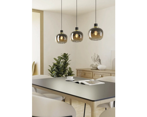 Trois suspensions avec abat-jour en verre rond au-dessus d'une table à manger.