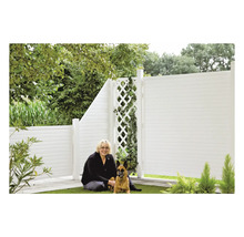 Frau mit Hund vor einem weißen Gartenzaun