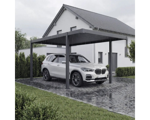 Carport métallique moderne avec voiture sur allée pavée devant la maison.