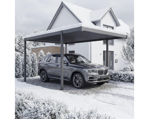 Une voiture est garée sous un abri devant une maison en hiver.