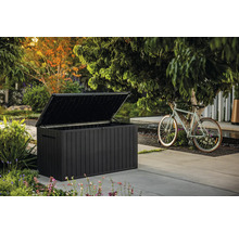 Geöffnete, dunkle Gartentruhe neben einem Fahrrad im Außenbereich.