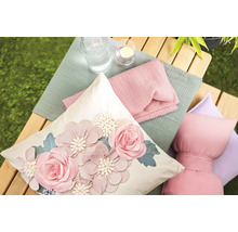 Dekorative Kissen und Textilien auf einer Holzbank im Garten.