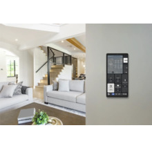 Panneau de commande mural Smart Home dans un salon lumineux et moderne avec canapé et escalier.