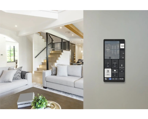 Panneau de commande mural Smart Home dans un salon lumineux et moderne avec canapé et escalier.