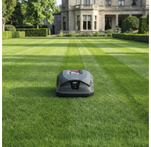 Rasenmähroboter auf einem Rasen vor einem Wohnhaus