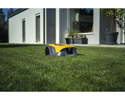 Robot tondeuse à gazon jaune sur une pelouse devant une maison