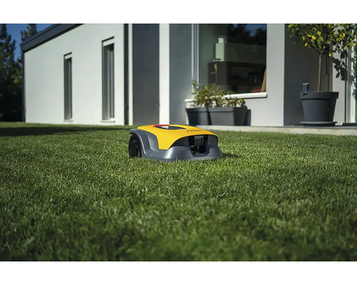 Gelber Rasenmähroboter auf Rasen vor einem Haus