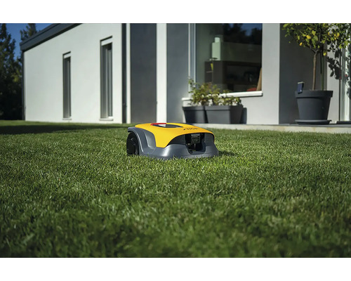 Gelber Mähroboter auf einer Rasenfläche vor einem Haus