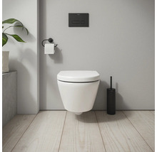 Wandhängendes WC mit Betätigungsplatte, Toilettenpapierhalter und Toilettenbürste in einem Badezimmer.